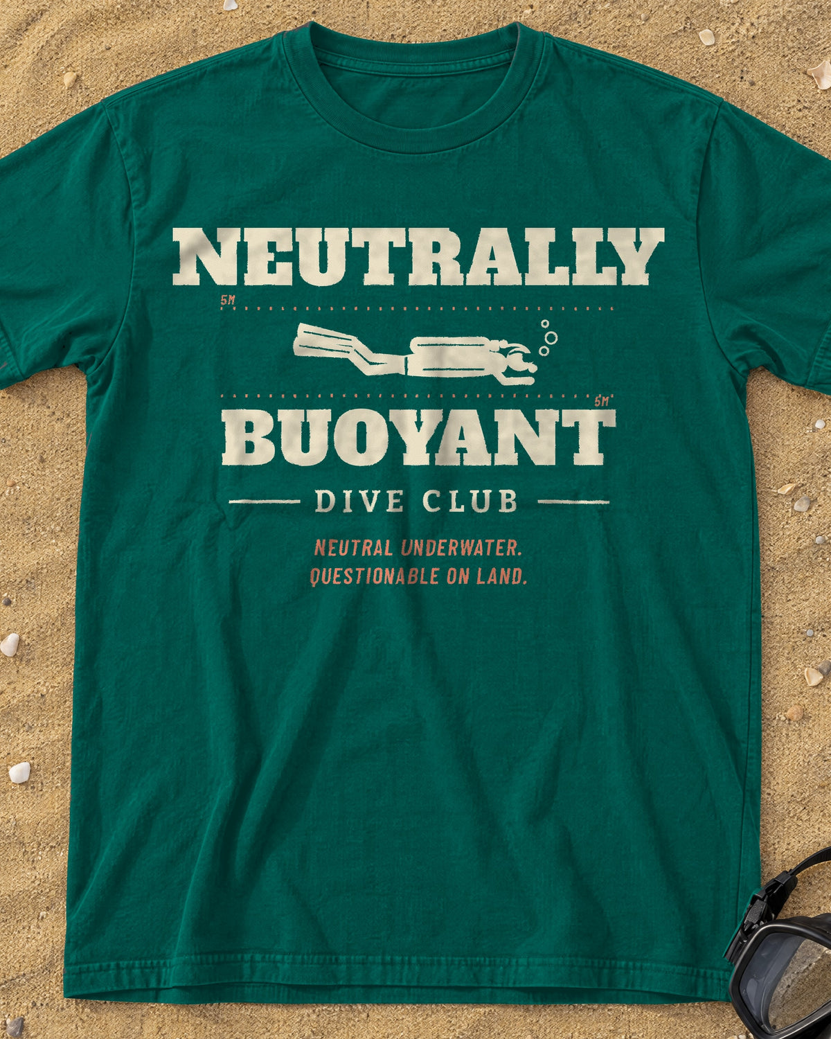 Blue Spruce Neutrally Buoyant Dive Club tee on a sandy beach