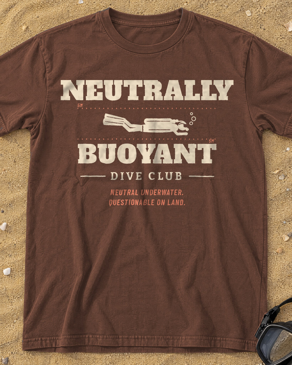 Espresso Neutrally Buoyant Dive Club tee on a sandy beach