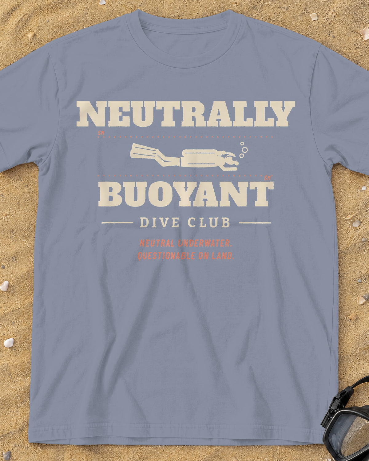 Washed Denim Neutrally Buoyant Dive Club tee on a sandy beach